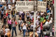 Multidão de pessoas andando em rua movimentada com placas indicando "Porto Geral" e "25 de Março".
