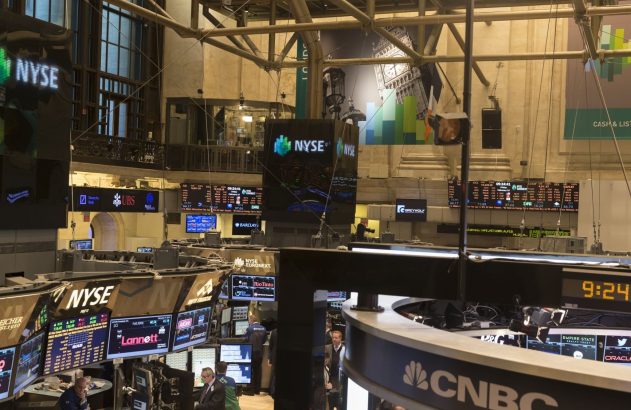 Salão da NYSE com telas de dados, traders e o logo CNBC. Horário 9:24 visível.