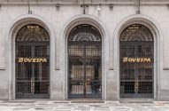 Fachada do prédio da Bovespa, com três grandes arcos e janelas com grades, exibindo o nome BOVESPA em dourado.