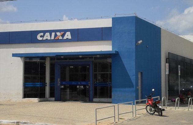 Agência da Caixa Econômica Federal azul e branca, com letreiro "CAIXA" e motos estacionadas em frente.
