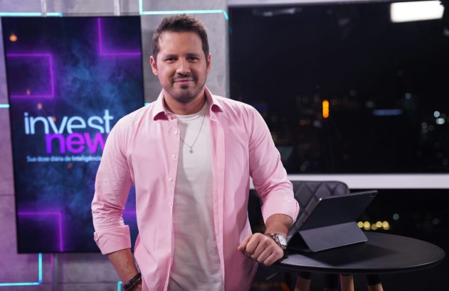 Apresentador de camisa rosa sorrindo em estúdio com tela "invest new".