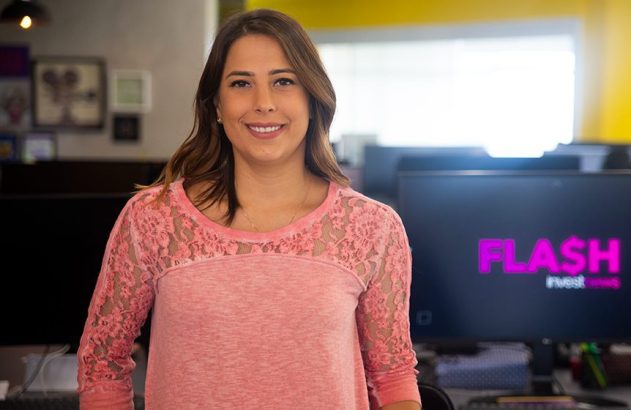 Mulher sorrindo em escritório com monitor exibindo o logo "FLASH invest".