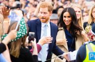 Príncipe Harry e Meghan Markle interagem com o público, que tira fotos e entrega presentes.