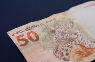 Cédula de 50 Reais do Brasil com uma onça-pintada, em close-up, sobre fundo azul-escuro.
