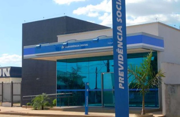 Prédio da Previdência Social com fachada de vidro azul e placas azuis de identificação.