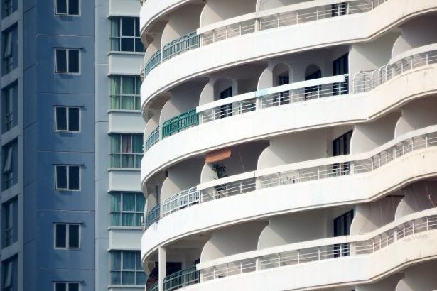 Edifícios residenciais: um branco curvo com sacadas, outro azul retangular com janelas.