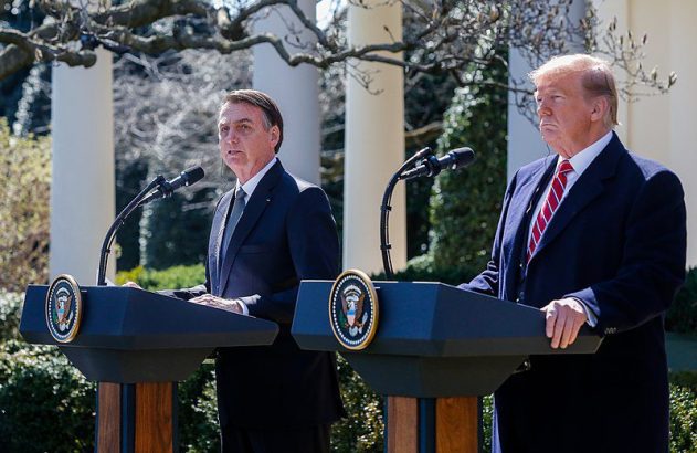 Presidentes Bolsonaro e Trump em coletiva na Casa Branca. Bolsonaro fala, Trump observa.