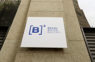 Placa branca da B3 Brasil Bolsa Balcão com logo [B]³, em azul, fixada na fachada de um prédio.