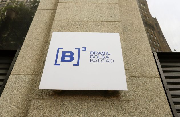 Placa branca da B3 Brasil Bolsa Balcão com logo [B]³, em azul, fixada na fachada de um prédio.