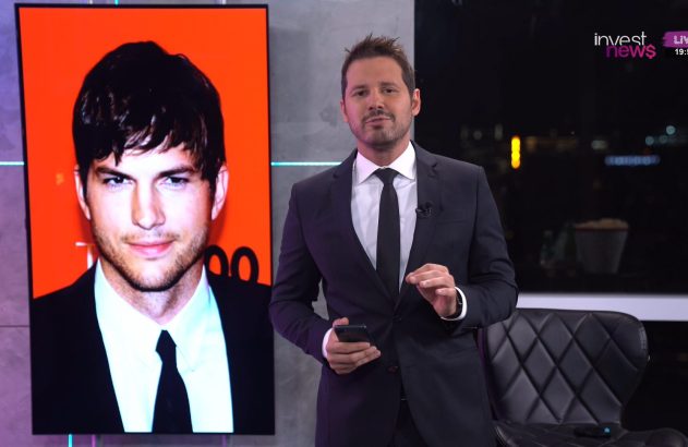 Apresentador de terno, com celular, ao lado de tela exibindo foto de Ashton Kutcher.