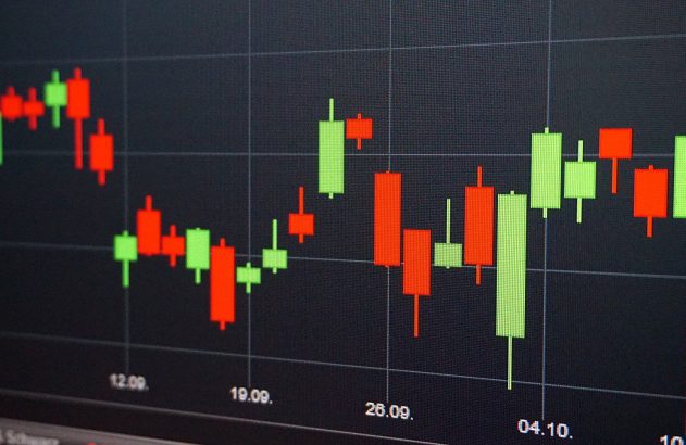 Gráfico de velas financeiro em tela escura, exibindo flutuações de preços com velas verdes e vermelhas.