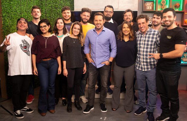 Grupo de colegas sorrindo e posando para a foto em ambiente de trabalho.