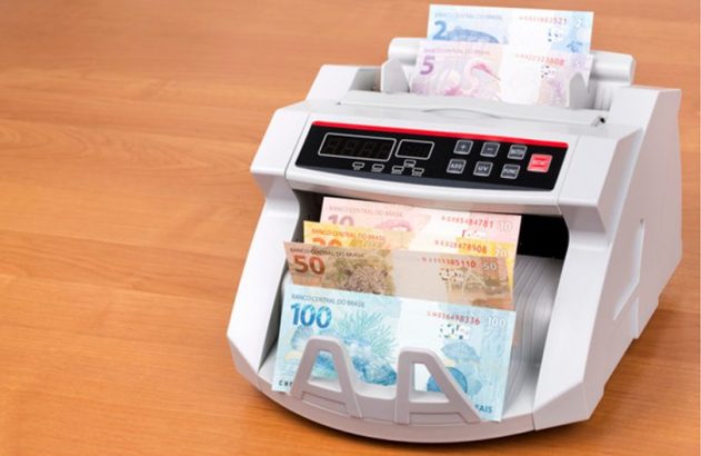 Máquina de contar dinheiro processando cédulas de Real.