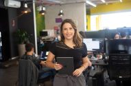 Mulher sorrindo, segurando um tablet, em um escritório.