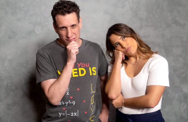 Homem e mulher com expressões pensativas e mãos no rosto, apoiados em parede cinza.