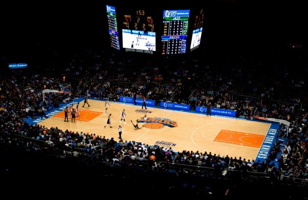 Jogo de basquete no Madison Square Garden. Placar: Knicks 57, Jazz 43. Jogador caído na quadra.