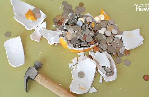 Cofrinho quebrado com moedas espalhadas e martelo ao lado.