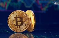 Duas moedas Bitcoin douradas sobre um fundo escuro com gráfico financeiro.