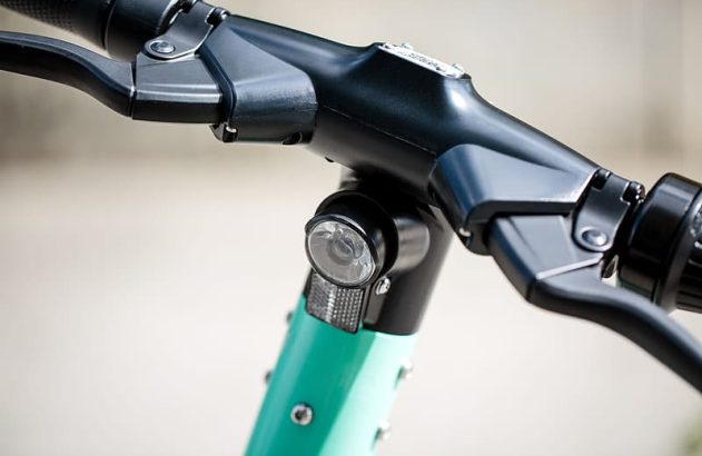 Guidão de patinete elétrico preto e verde com manetes de freio.