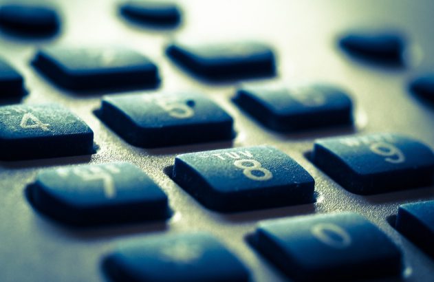 Close-up de teclas de calculadora com números 4, 5, 8, 9 e 0 visíveis, em tom azulado.