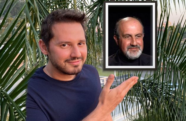 Homem sorridente aponta para foto emoldurada de homem mais velho barbudo. Palmeiras e vista da cidade ao fundo.