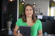 Mulher em camisa verde segura tablet em ambiente de escritório.