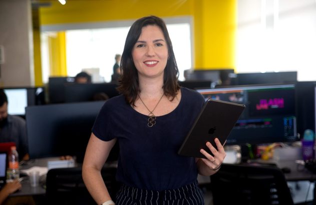 Mulher sorrindo segura tablet em escritório.