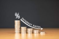 Queda das taxas de juros: símbolo %, moedas decrescentes, seta e texto 'INTEREST RATES'.