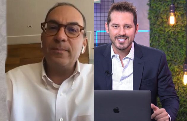 Dois homens em conferência online. Um usa óculos, outro sorri com laptop. Reunião virtual.