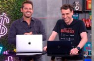 Dois homens sorridentes atrás de laptops (um MacBook) em estúdio com iluminação neon ao fundo.
