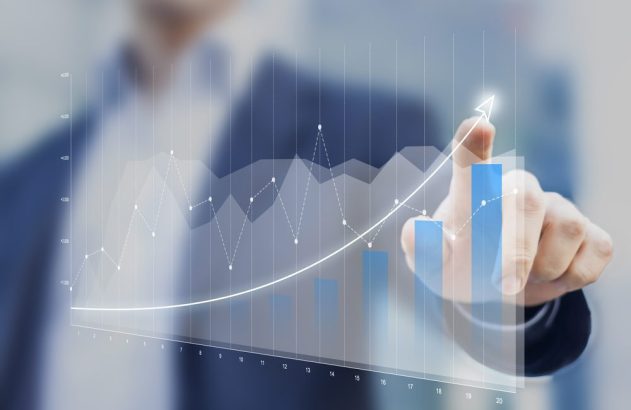 Mão apontando para gráfico digital de crescimento, com barras azuis e linha ascendente.