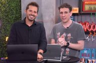Dois apresentadores em estúdio com laptops. Um sorri e o outro gesticula, em apresentação ou webinar.