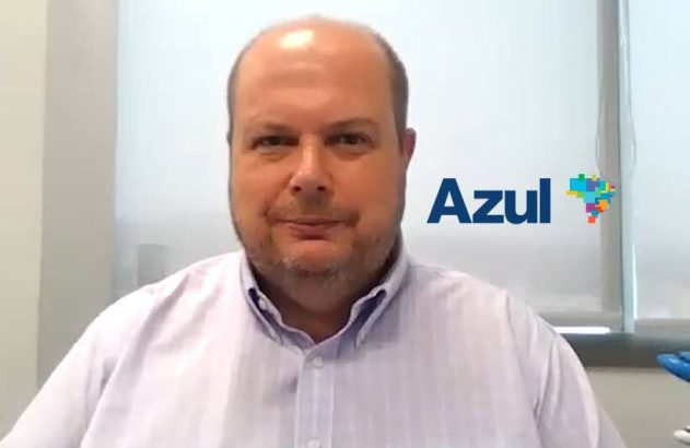 Retrato de homem sorrindo com logotipo da Azul Airlines ao fundo.