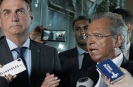 Jair Bolsonaro e Paulo Guedes em coletiva de imprensa. Guedes fala com microfones à frente; Bolsonaro atento.