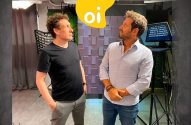 Dois homens em estúdio, olhando para o alto, onde se vê o logo "oi" amarelo.