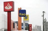 Fileira de letreiros de bancos em postes: Santander, Itaú, Banco do Brasil e Caixa.