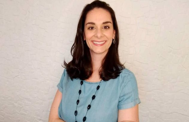 Mulher sorridente com cabelos escuros e blusa azul em retrato.