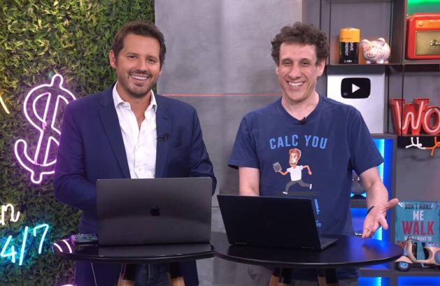 Duas pessoas sorrindo para a câmera em estúdio de gravação, com laptops em mesas.