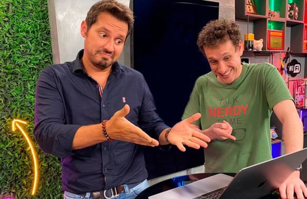 Dois homens em estúdio. Um gesticula com as mãos abertas, o outro olha intrigado para um teclado.