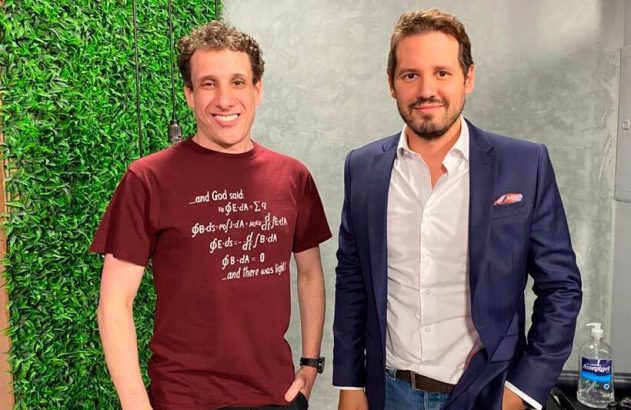 Dois homens, um de camiseta e outro de blazer, posam para a câmera.