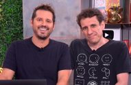 Dois homens em um estúdio. O da esquerda sorri. O da direita tem expressão neutra e veste camiseta com desenhos.