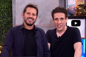 Dois homens sorrindo lado a lado em um estúdio.