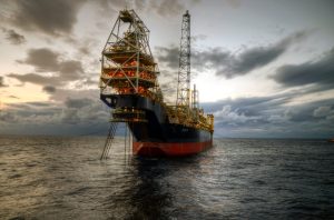 Navio-sonda de perfuração no oceano sob céu nublado.