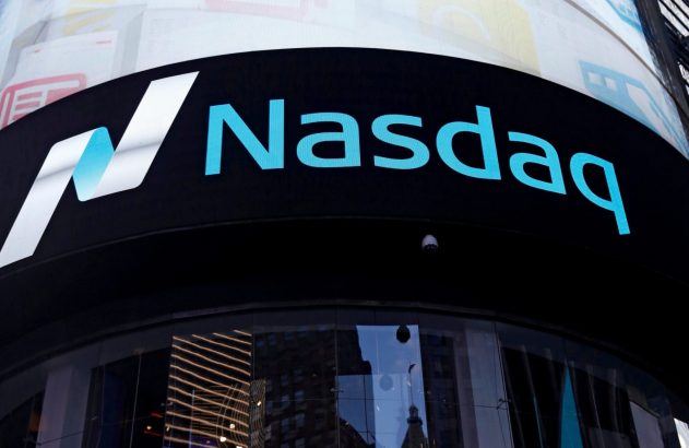 Sinal da Nasdaq: logo e nome em azul e branco, em fundo preto. Fica no topo de um prédio com reflexos nas janelas.
