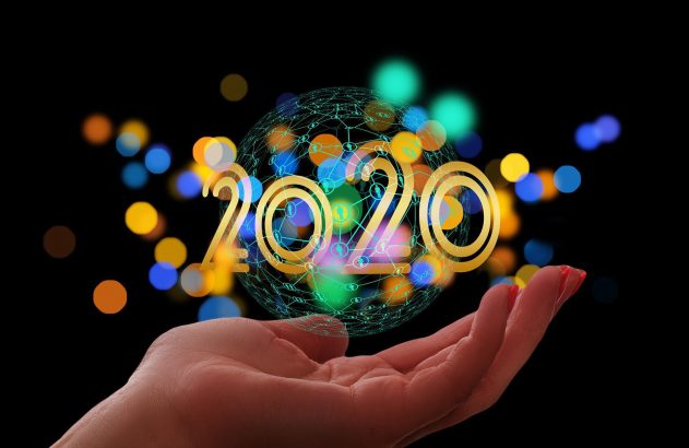 Mão segura esfera de rede digital com "2020" dourado. Fundo desfocado e escuro com pontos de luz coloridos.