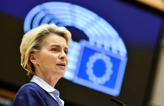 Mulher loira discursando. Fundo azul com ícone do Parlamento Europeu.