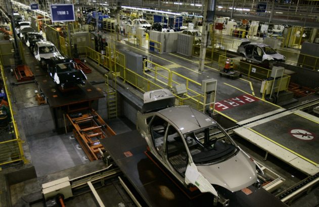 Linha de montagem de carros em uma fábrica, com veículos sendo montados.