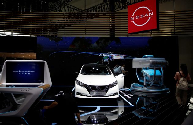 Estande Nissan: carro Leaf branco, tela "Intelligent Mobility", pessoas explorando inovações sob o logo Nissan.