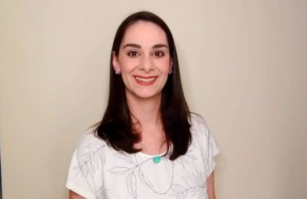 Mulher de cabelo escuro e blusa clara sorrindo para a câmera.