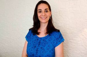 Retrato de mulher sorridente com cabelo escuro e blusa azul.
